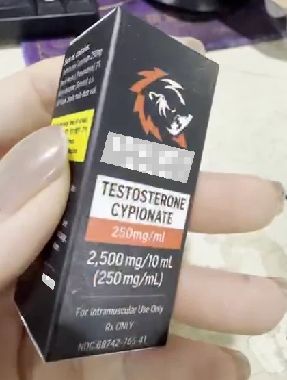 Real front-and-side view of a printed carton held in a hand, with a light brand-name mosaic