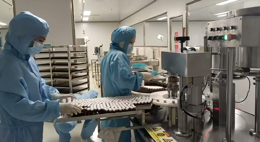 Production-floor reference showing technicians and vial line handling